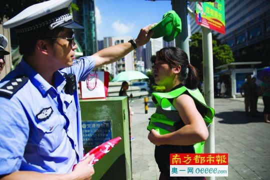  昨日，罗湖区一十字路口一女子闯红灯被抓，很配合地穿上绿马甲戴上绿帽子。南都记者 陈文才 摄