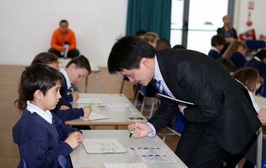 3月17日，在英国伦敦东北部埃塞克斯郡的哈里斯小学，金向军老师为学生批改课堂练习