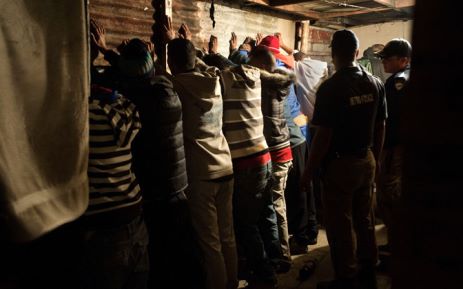 A group of men stand with their hands against the wall after the house where they were gambling was raided during a combined Metro Police and South African Police Services operation to arrest suspects, and search for drugs and firearms, in Manenburg, on 27 August 2013. Picture: AFP.