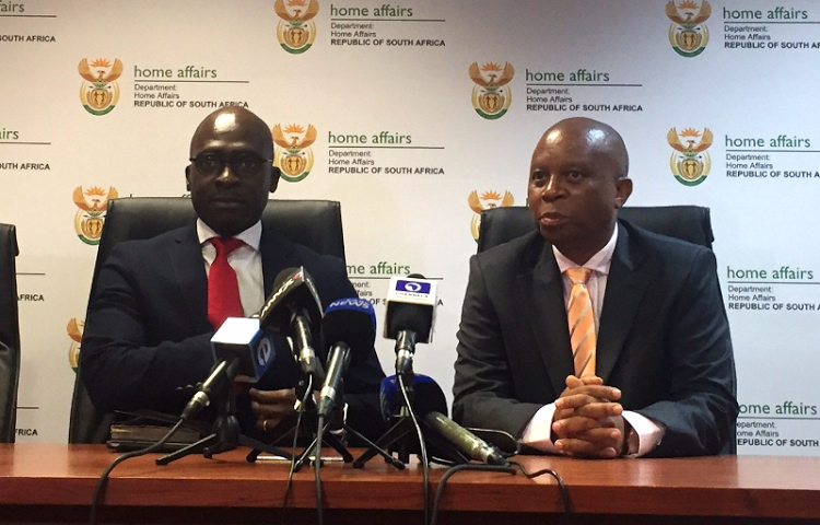 Malusi Gigaba, left, and Herman Mashaba speak to reporters during a media briefing at the Home Affairs head office in Pretoria.   Picture: NEO GOBA