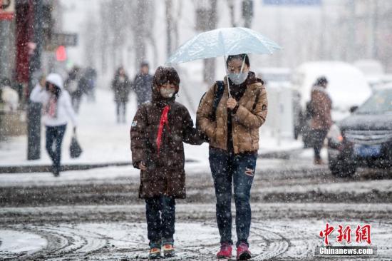 21日，太原街头，家长冒着大雪送孩子上学。 中新社记者 韦亮 摄