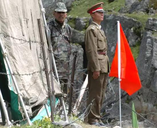 ▲资料图片：2006年7月5日，在中印边境锡金段乃堆拉山口，一名中国边防军人（右）与一名印度边防军人隔着边界的铁丝网值勤。