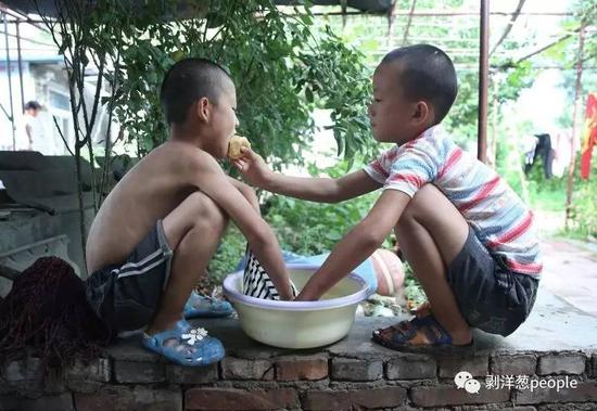 “濮阳市艺术公益培训基地”，一名小朋友在洗衣服，他最好的“哥们儿”陪着他，正和他分享一个苹果。