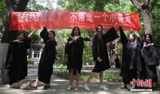 6月9日，几名毕业生在北京工业大学校园内合影，校园里悬挂着北京部分高校毕业季里特有的“任性”条幅。中新社记者 杨可佳摄